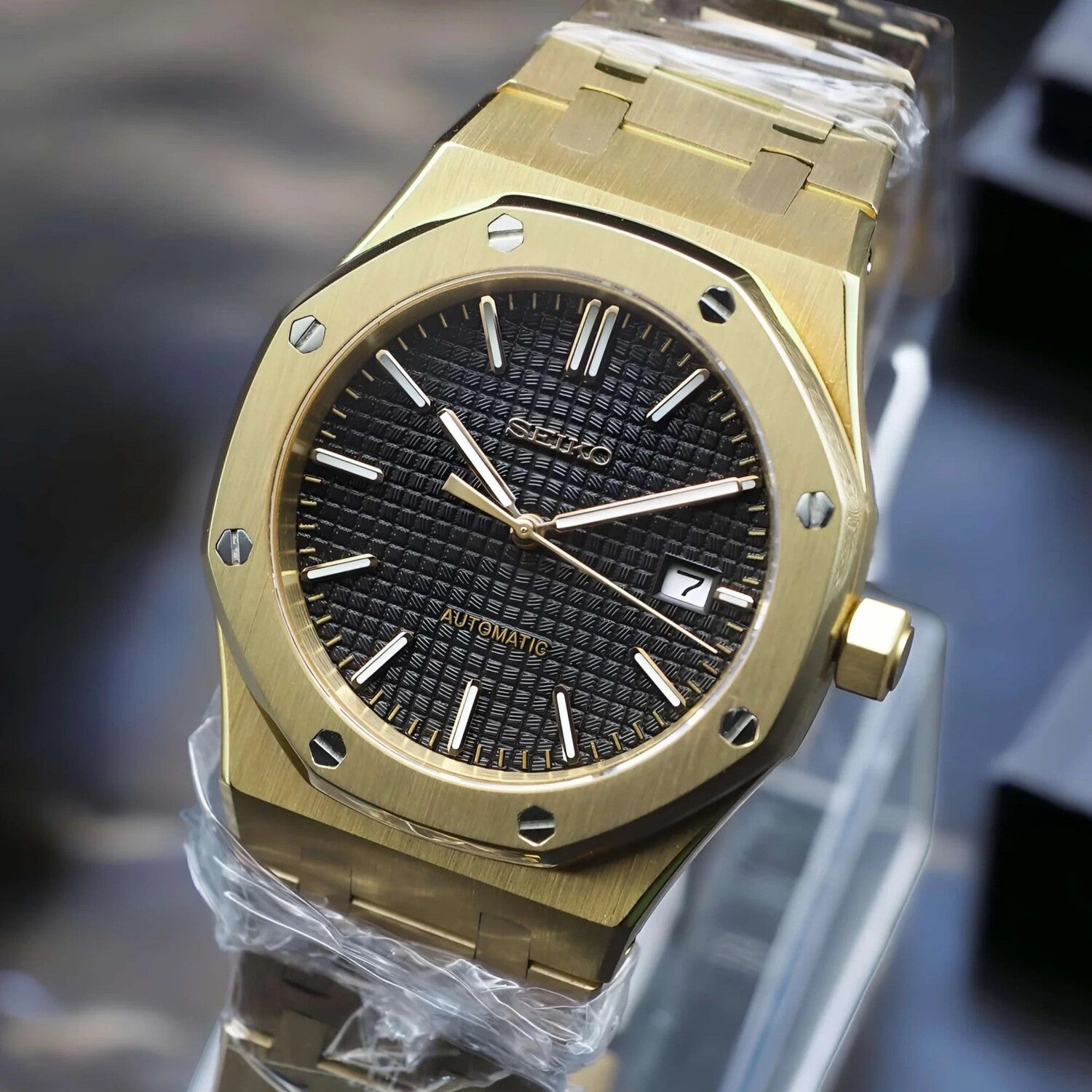 Right angled view of Seiko Mod Royal Oak in yellow gold, showing the brushed bezel, black textured dial, and applied indices.