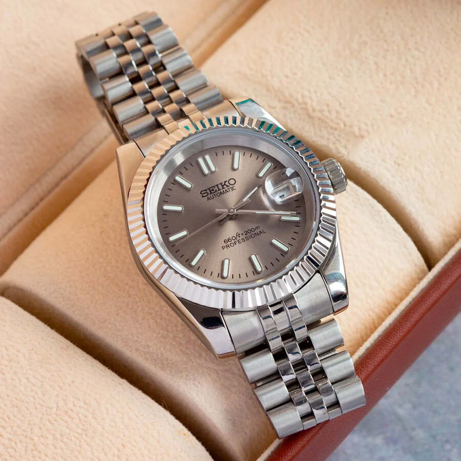Top view of Seiko Mod Datejust showing champagne dial and Jubilee bracelet inside beige watch box