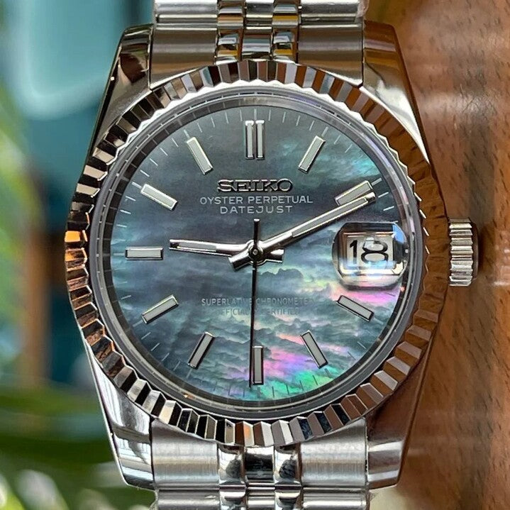 Seiko Mod Datejust Cosmos close up of iridescent black dial with silver hour markers and fluted bezel reflecting turquoise tones