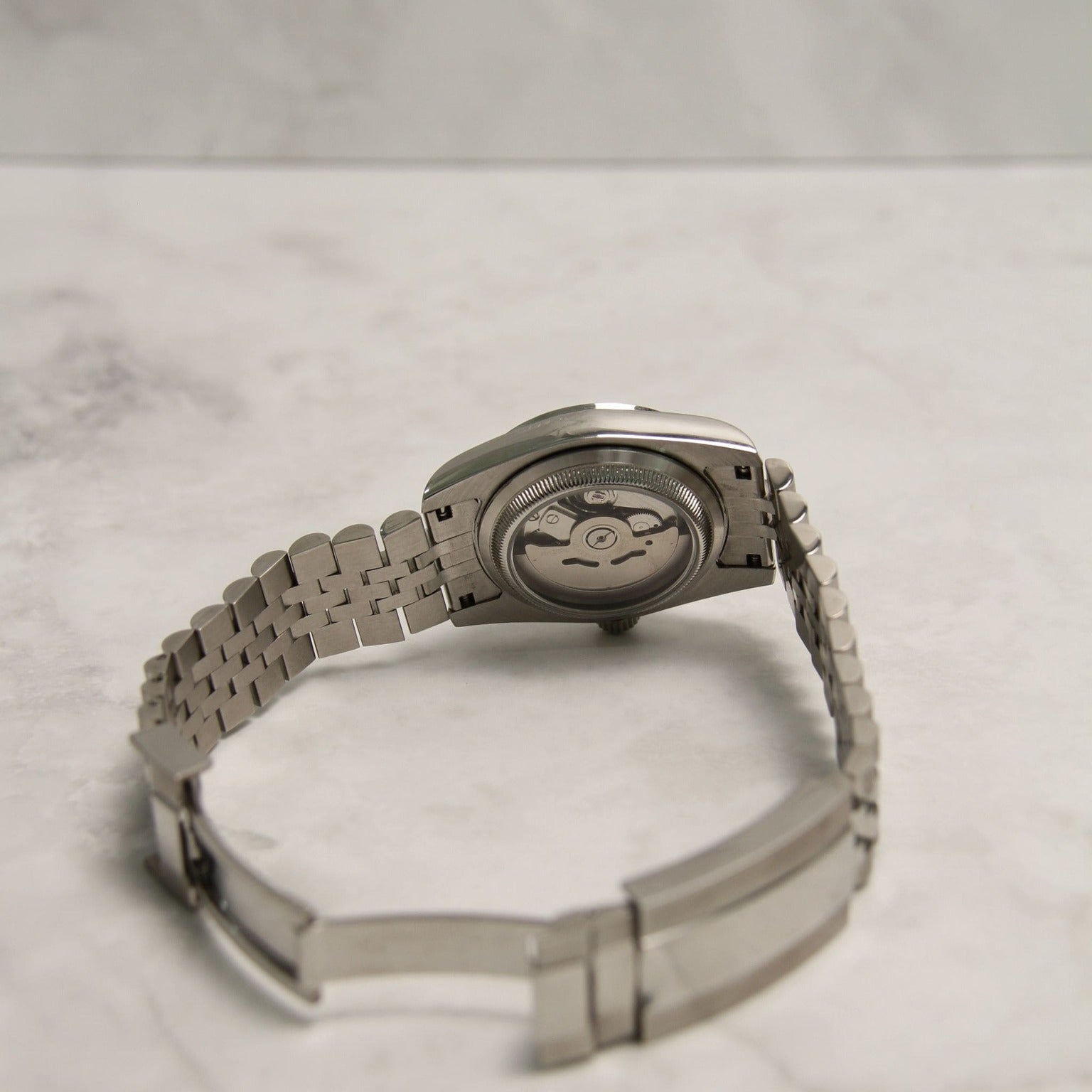 Seiko Mods Datejust Grey Smooth Bezel Clear Case Movement on marble background, rear view showing automatic rotor