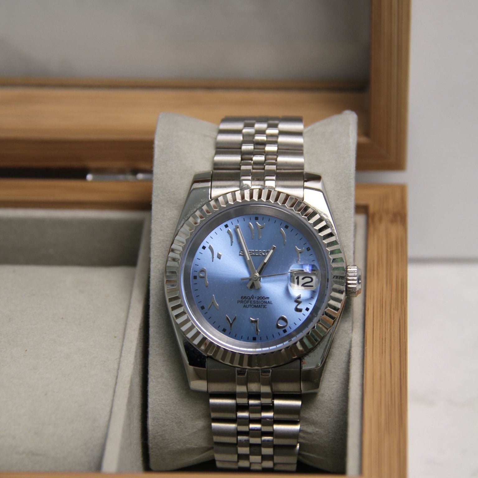Front view of Seiko Mod Datejust Ice Blue Arabic dial in a wooden box with silver jubilee bracelet