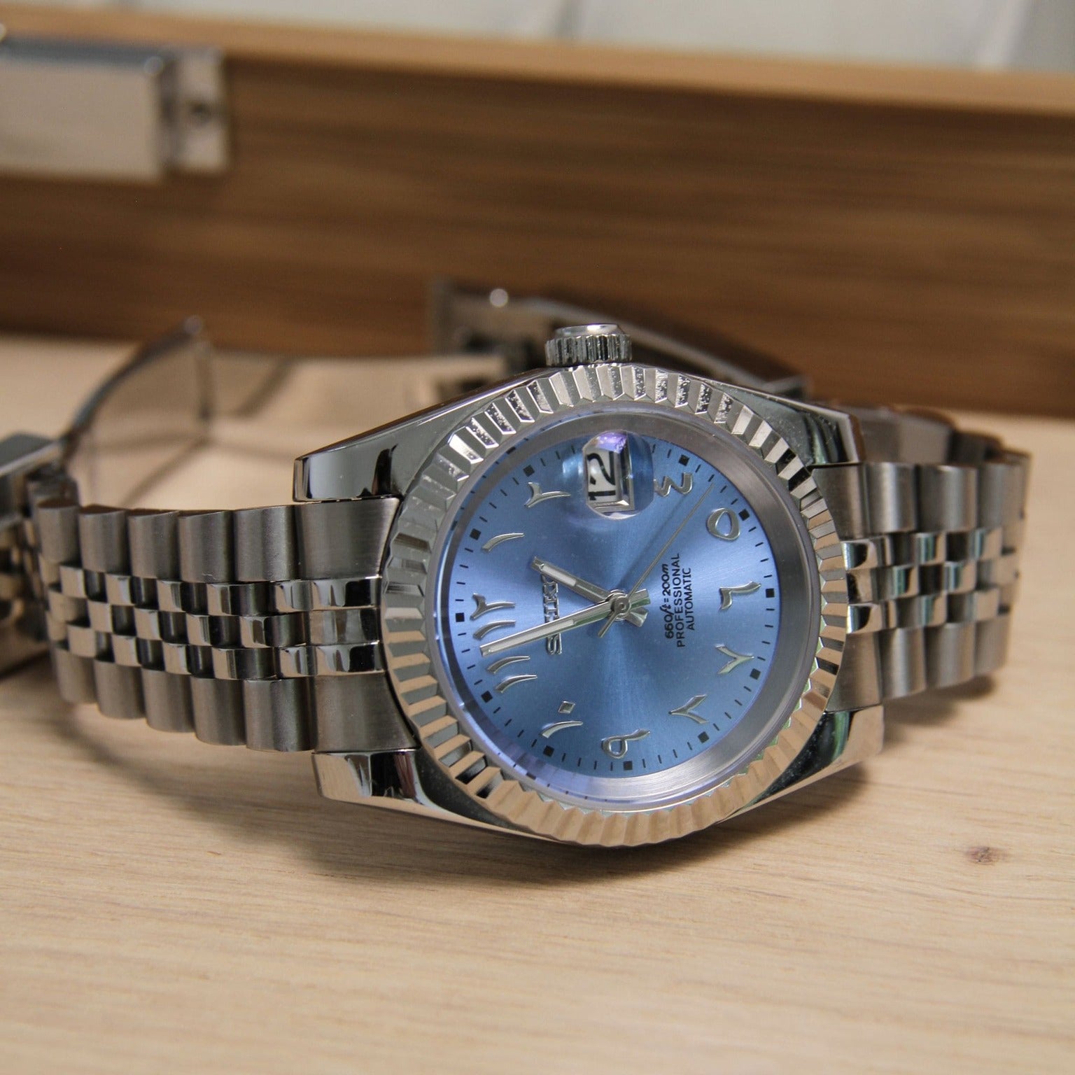 Seiko Mod Datejust Ice Blue Arabic watch resting horizontally showing reflective sunburst dial
