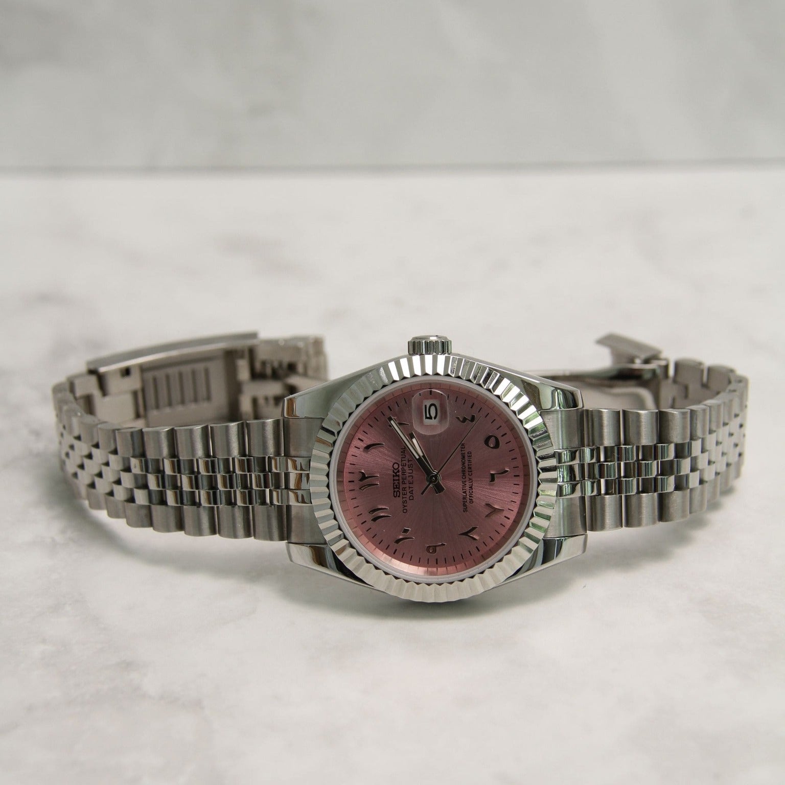 Seiko Mods Datejust Rose Arabic laid flat on marble surface Horizontal view