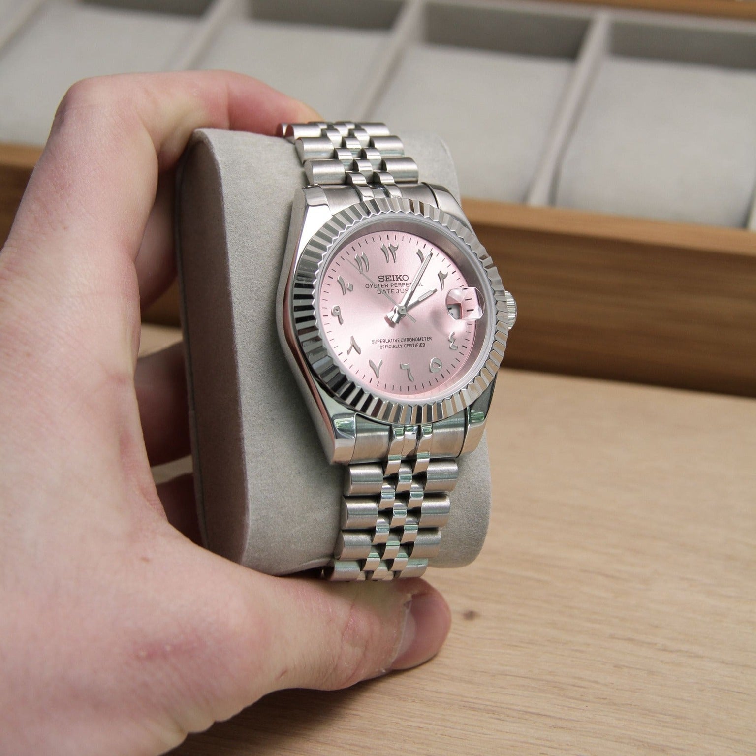 Seiko Mods Datejust Rose Arabic held in hand on soft pillow with clear dial reflection