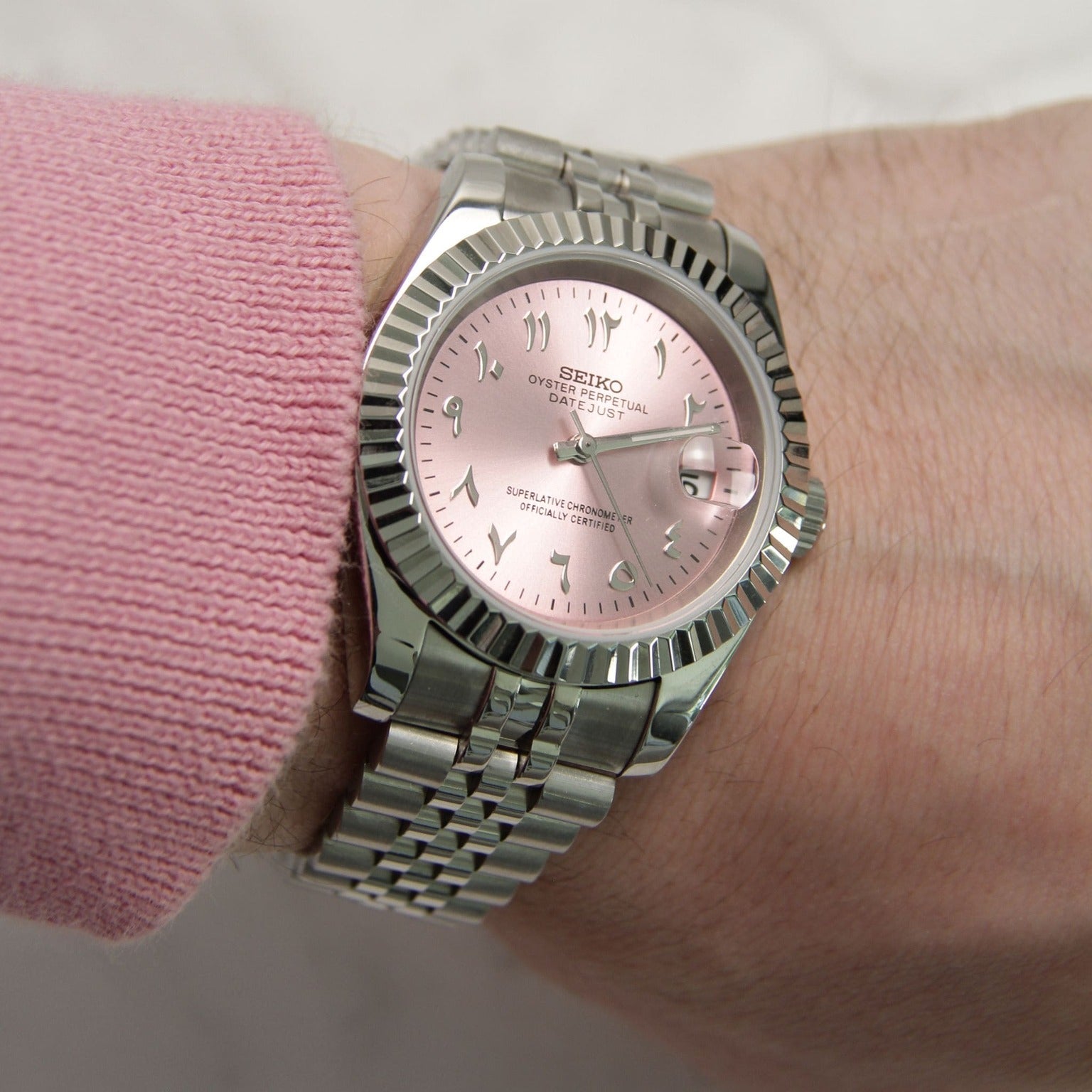 Seiko Mods Datejust Rose Arabic worn on wrist with pink sweater in natural lighting