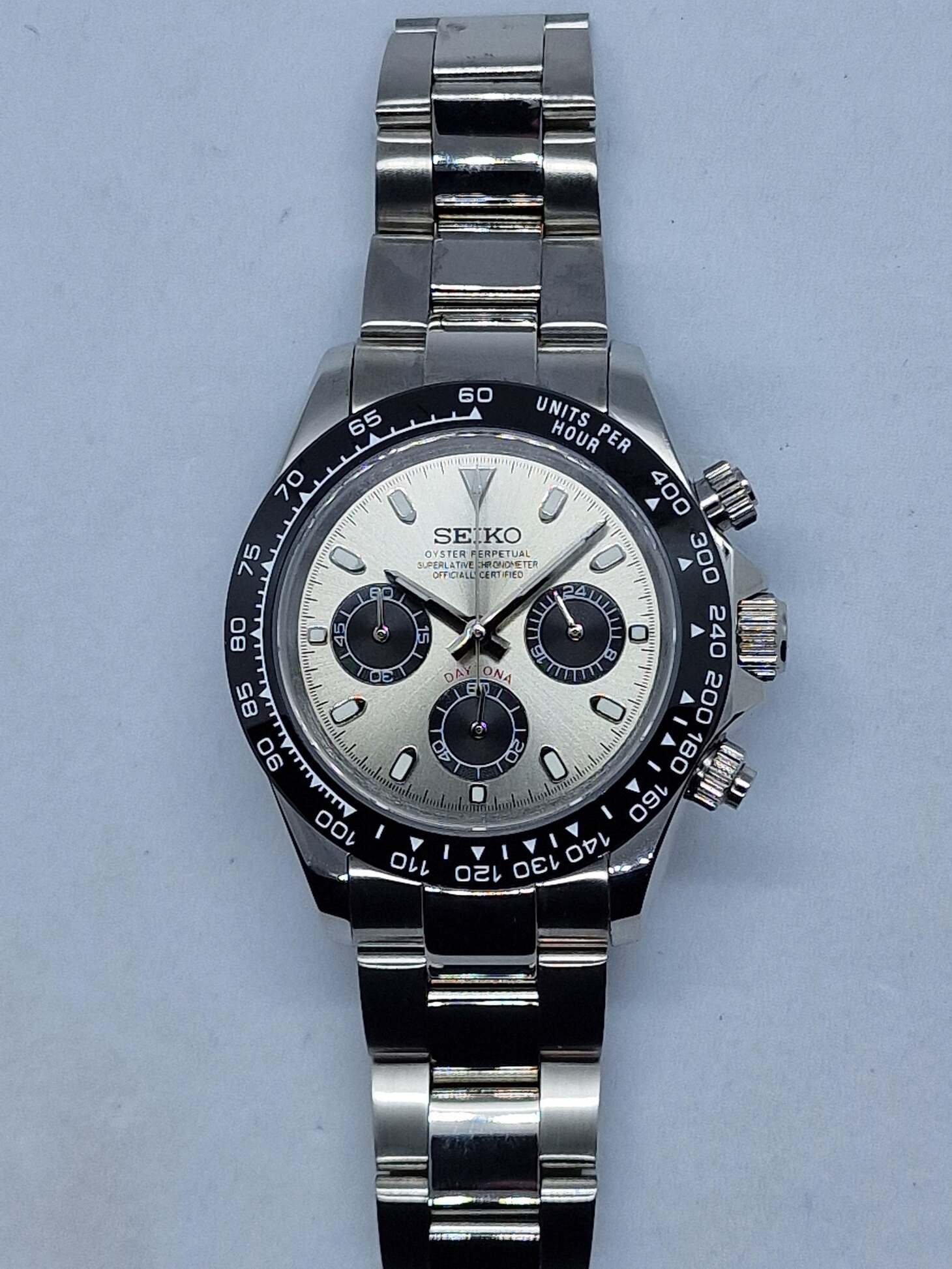 Front view of a Seiko Mod Daytona with champagne dial, black ceramic bezel, and stainless steel bracelet.