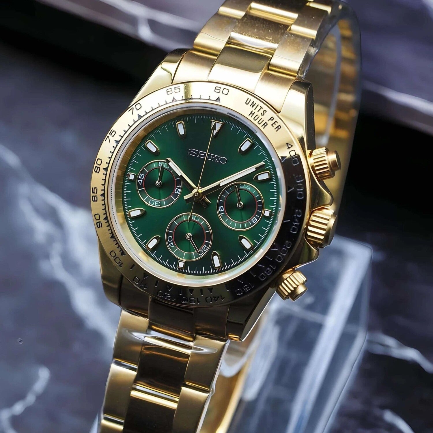 Right angled view of the Seiko Mod Daytona in yellow gold showcasing a rich green dial, three golden rimmed subdials, and a polished oyster bracelet.