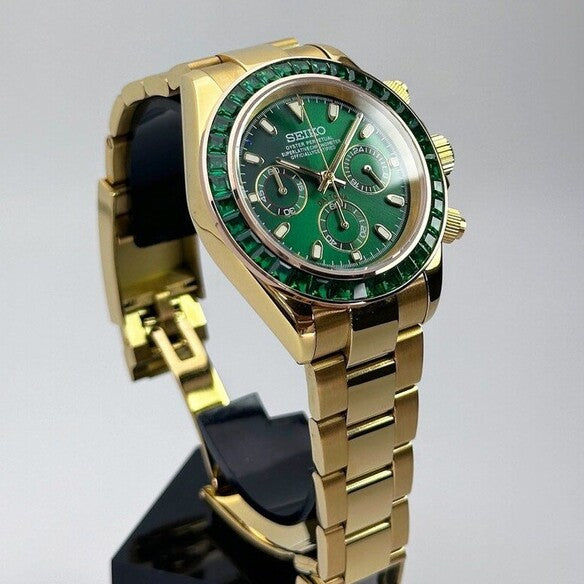 Seiko Moddys Daytona Green Emerald angled view showing gold bracelet, emerald bezel and sunburst green dial.