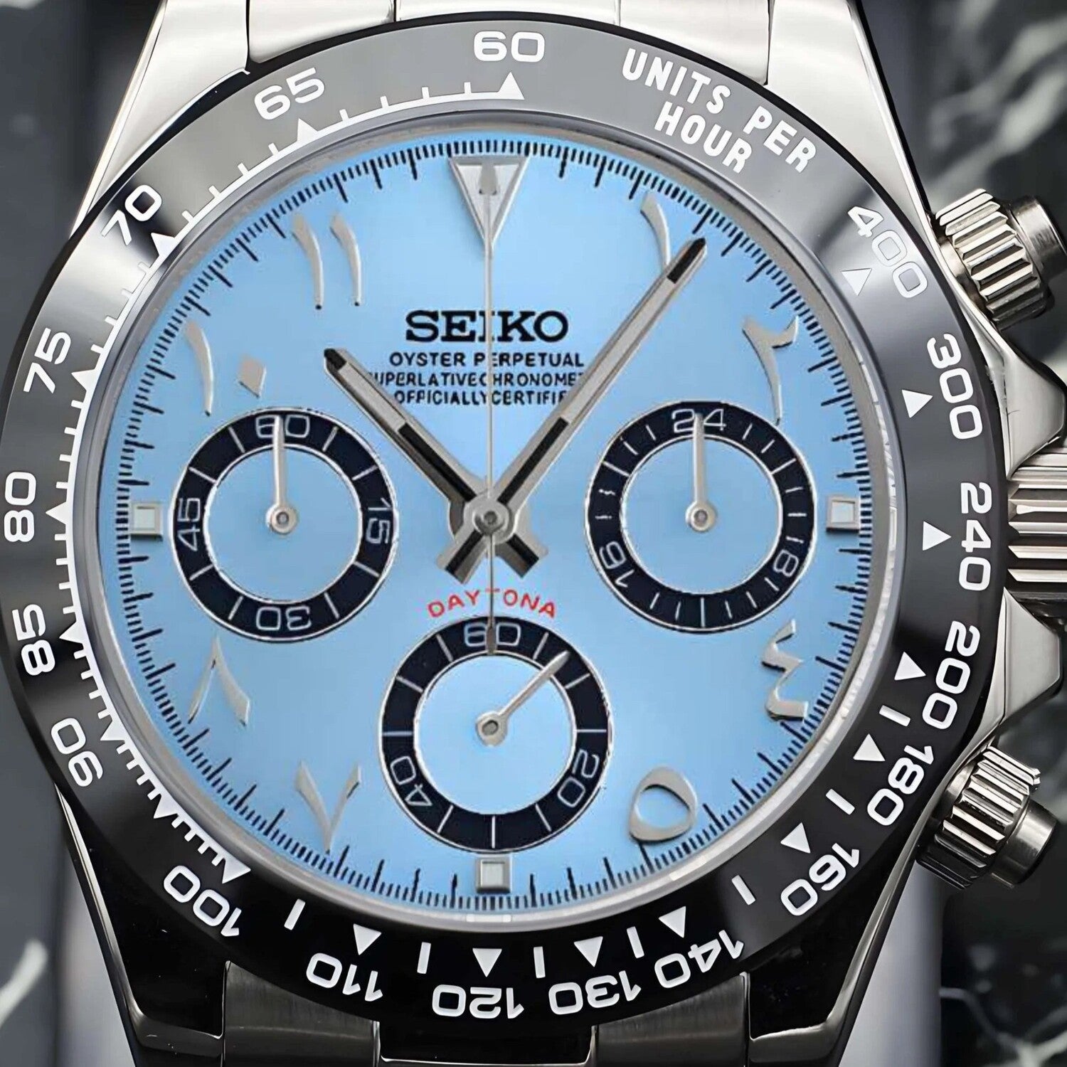 Close up front view of a Seiko Mod Daytona with ice blue Arabic dial, black ceramic bezel and steel case.