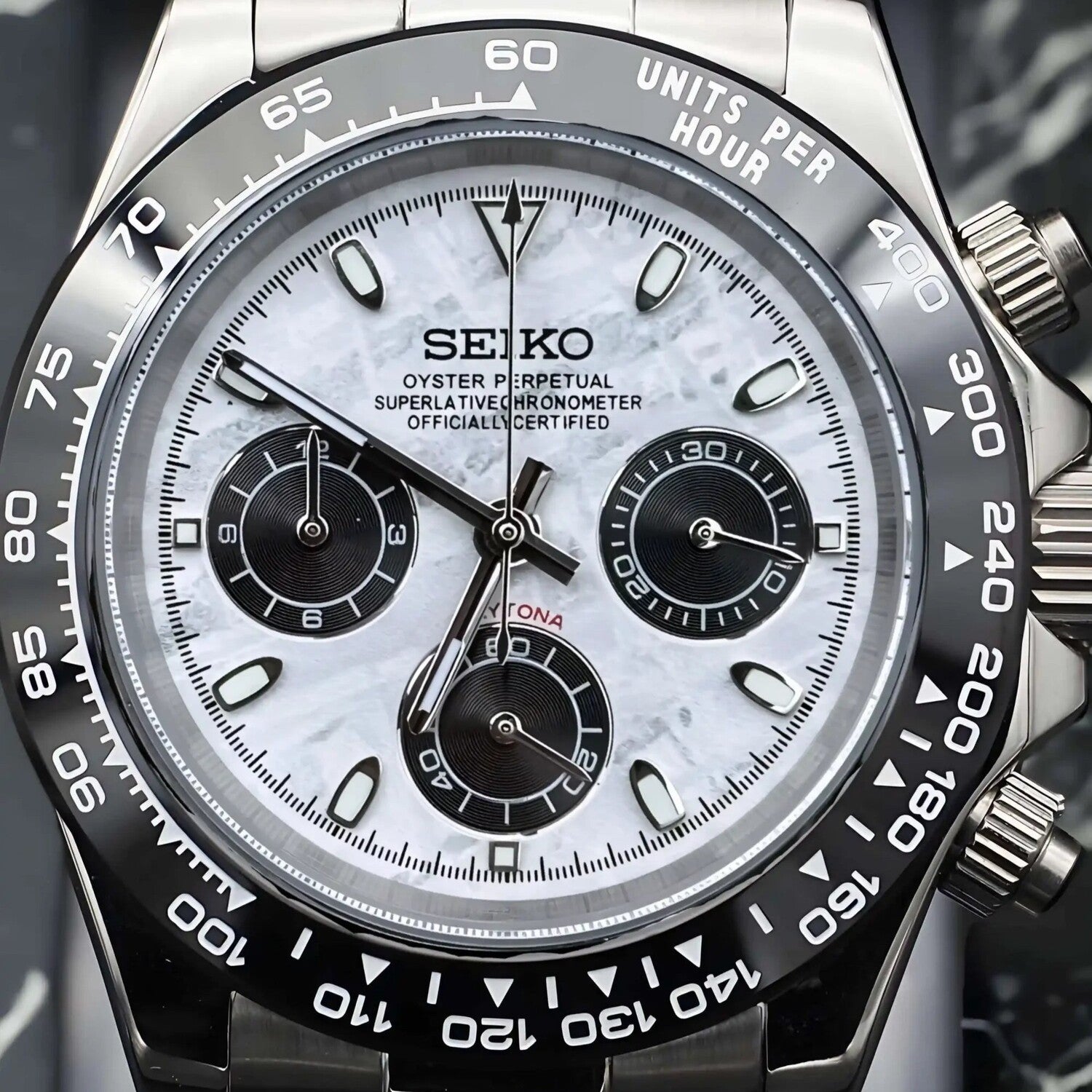 Close up view of Seiko Mod Daytona with meteorite textured white dial, black ceramic bezel and three black subdials, captured from the front.