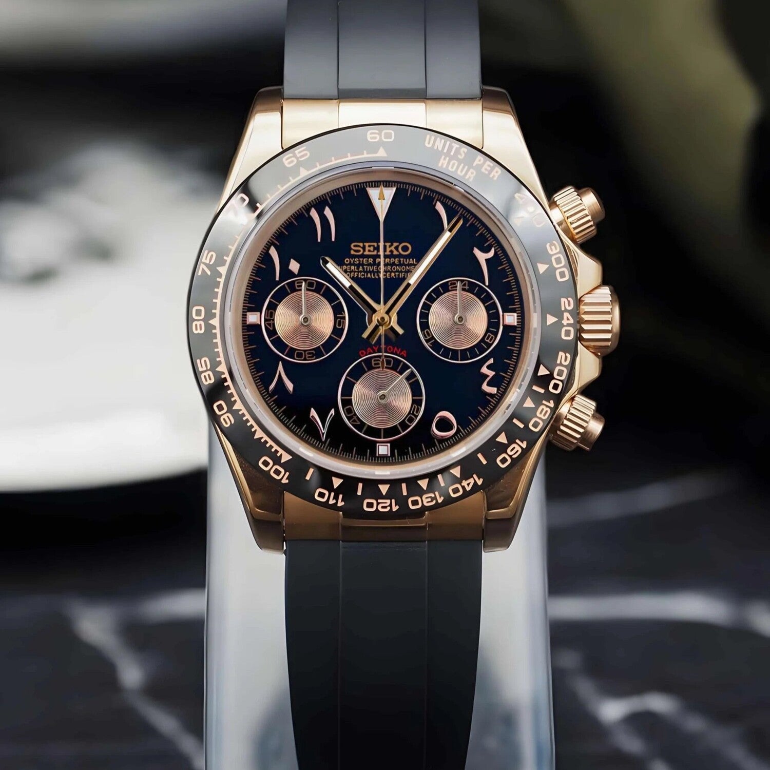 Seiko Mod Daytona Rose Gold Arabic front view featuring black dial, gold subdials, engraved tachymeter bezel and black rubber strap.
