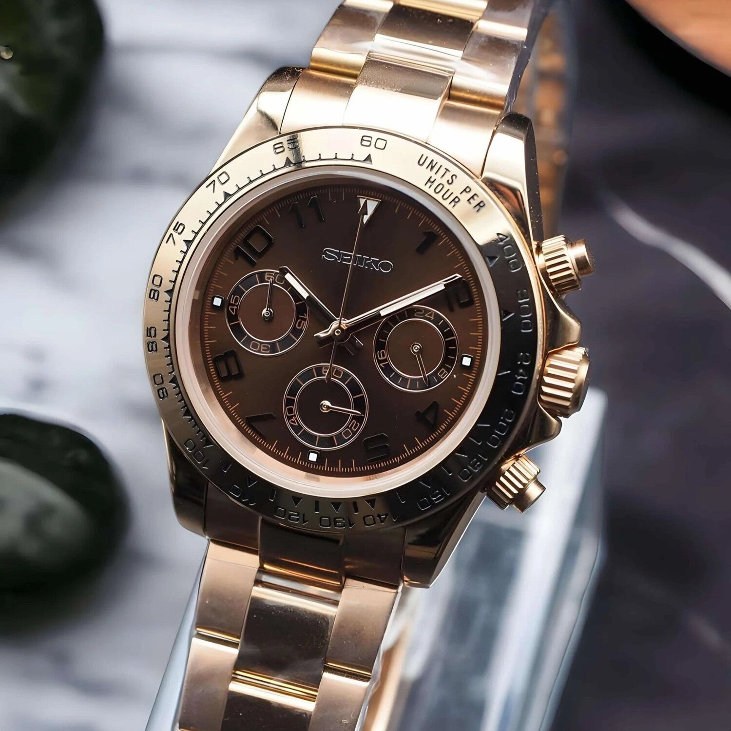 Right-angled close up of the Seiko Mod Daytona in rose gold with chocolate dial showing side pushers and bracelet links.