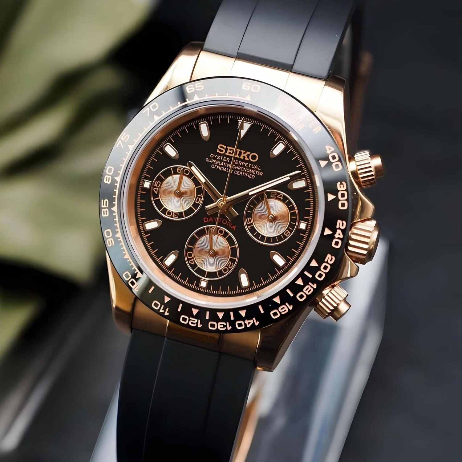 Right three quarter angle of the Seiko Mod Daytona in rose gold with black rubber strap, showing crown, pushers, and ceramic bezel.