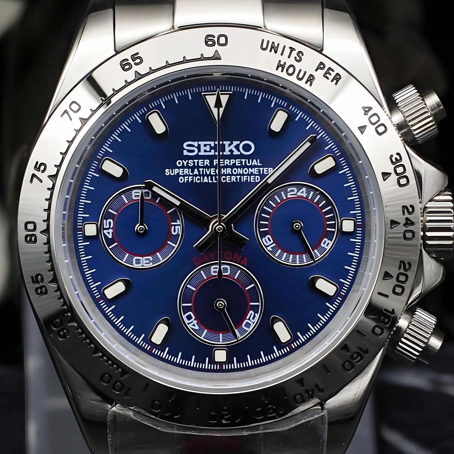 Close up of Seiko Mod Daytona with metallic royal blue dial, silver subdials, polished steel bezel and crown detail.