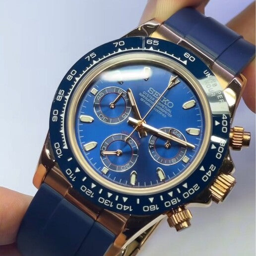 Seiko Mod Daytona Royal Blue angled view showing sunburst dial, rose gold pushers and navy rubber strap.