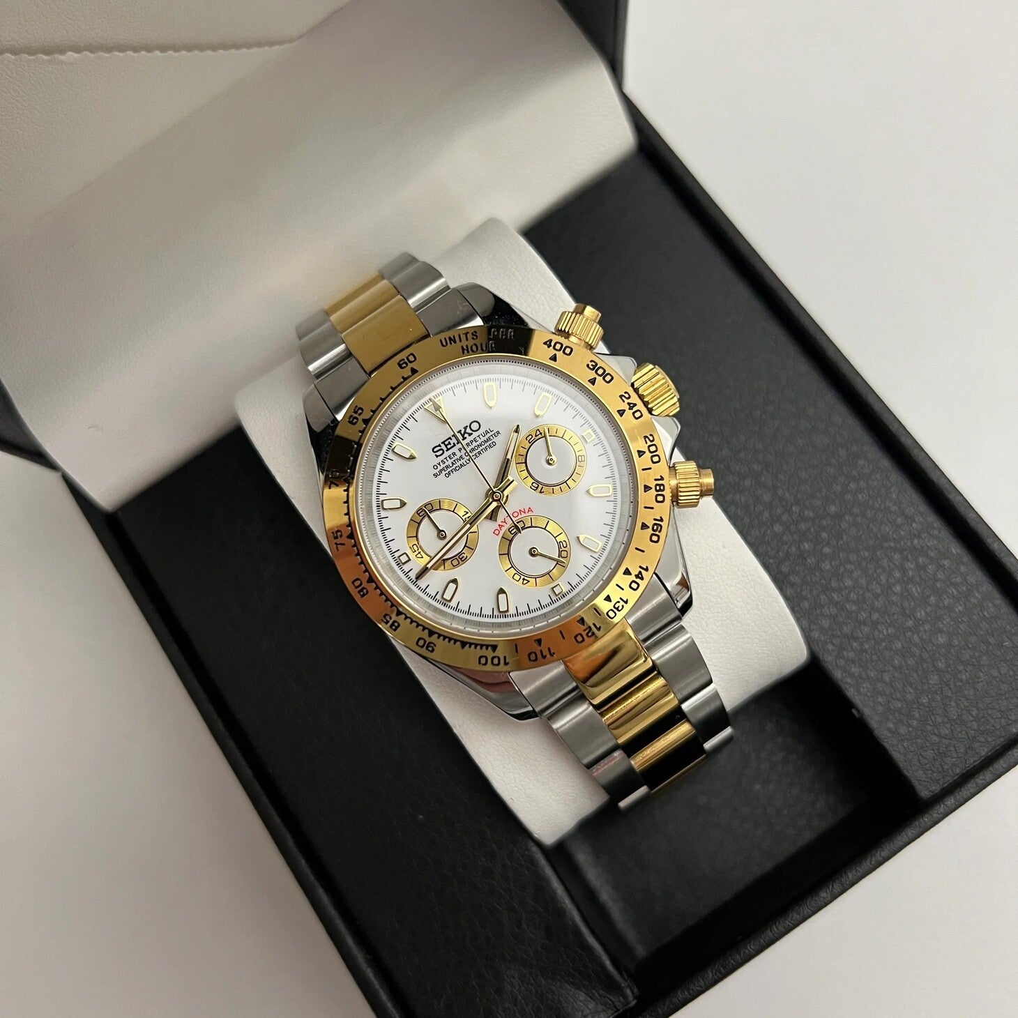 Seiko Mod Daytona steel and gold with white dial, showcased inside a black watch box with cushion support.