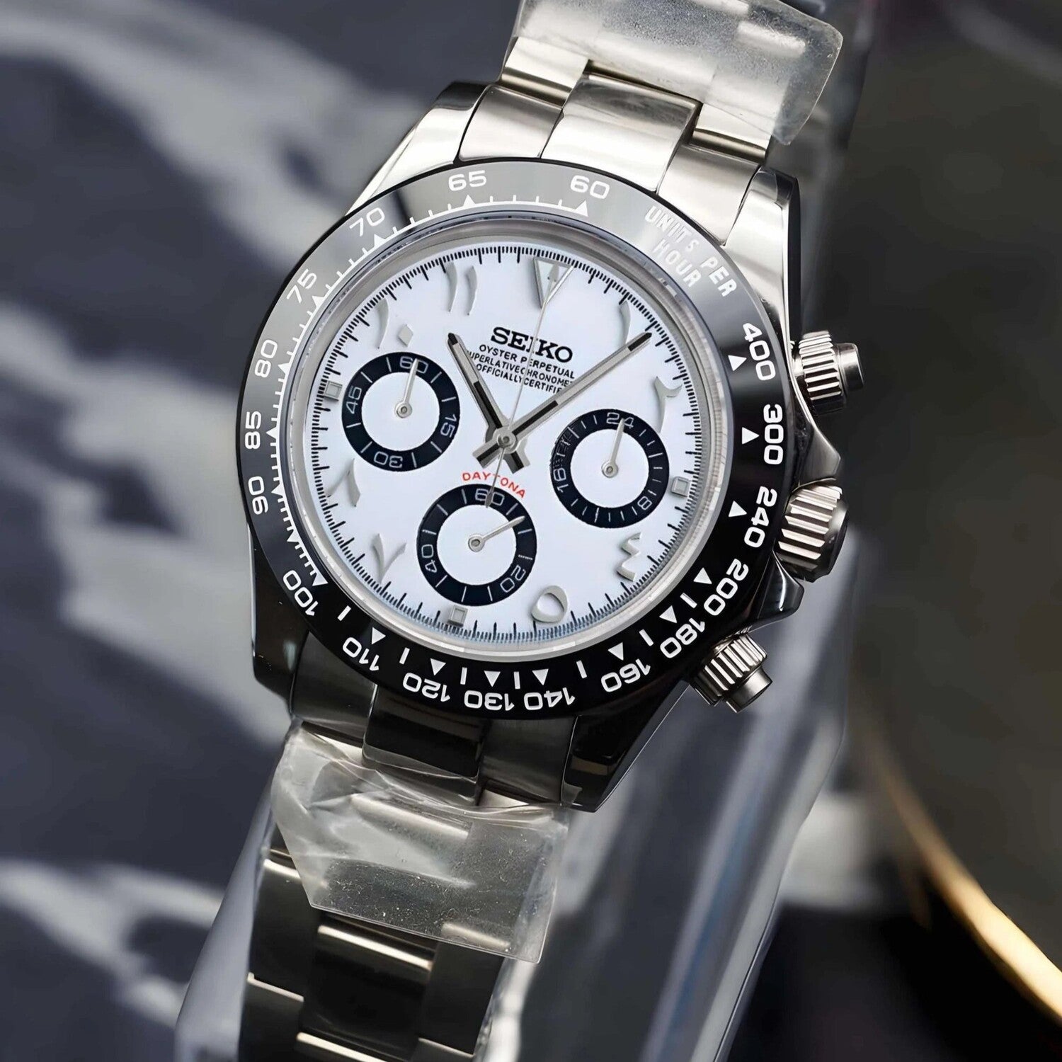 Right angled close up of Seiko Mod Daytona white Arabic dial stainless steel bracelet and black bezel