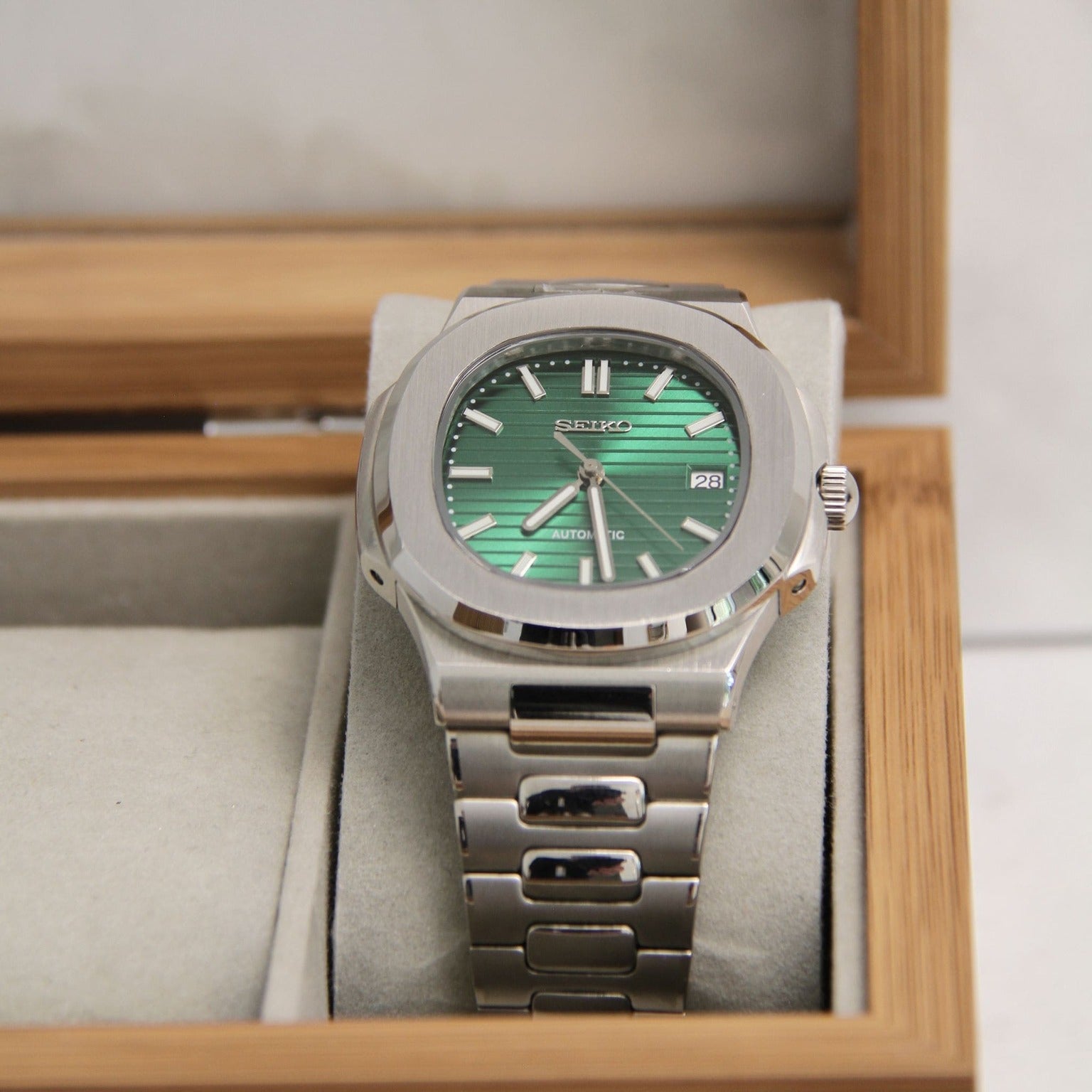 Seiko mod Nautilus green metallic dial displayed in a wooden presentation box with integrated bracelet