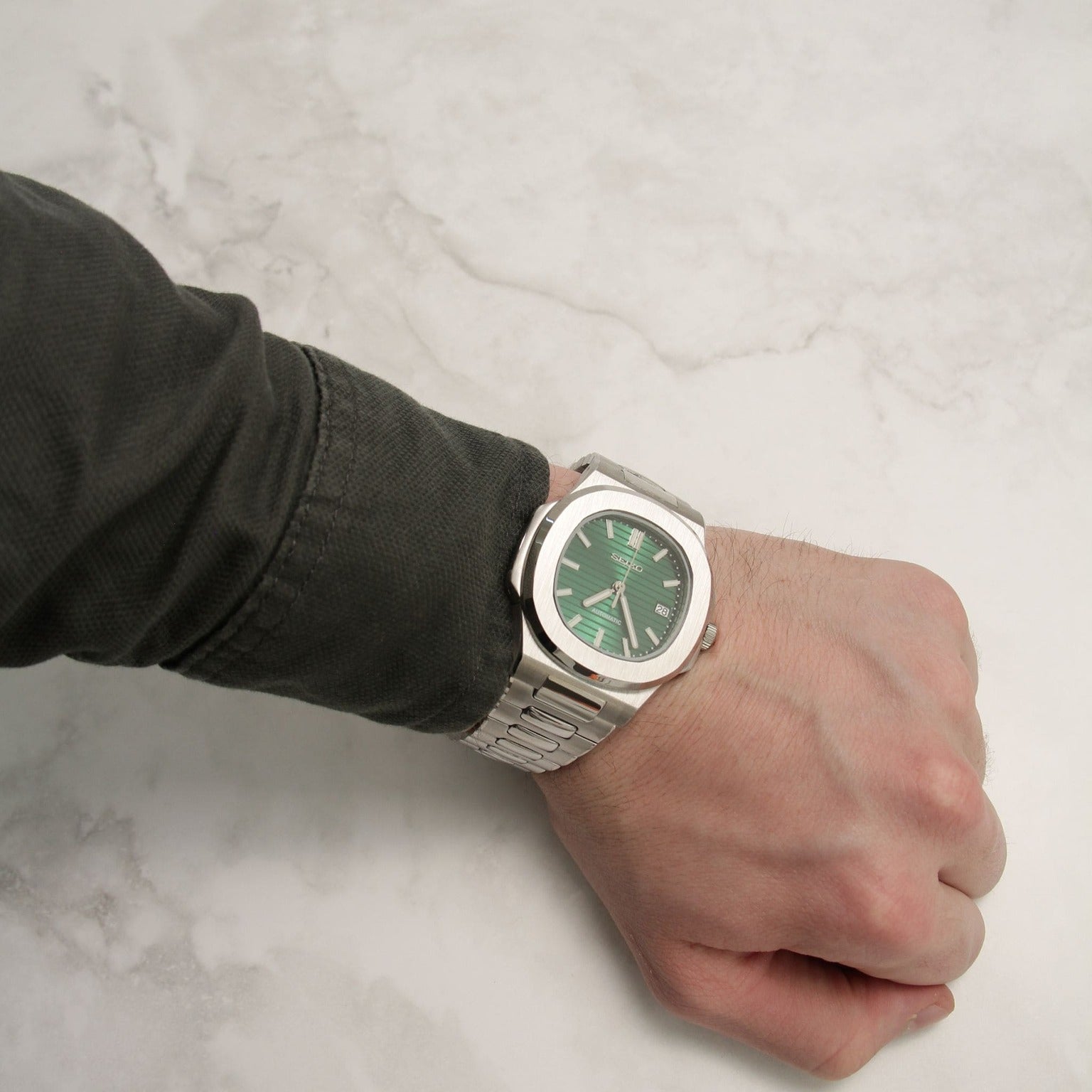 Wrist view of Seiko mod Nautilus green metallic showing proportions and light reflection on the dial