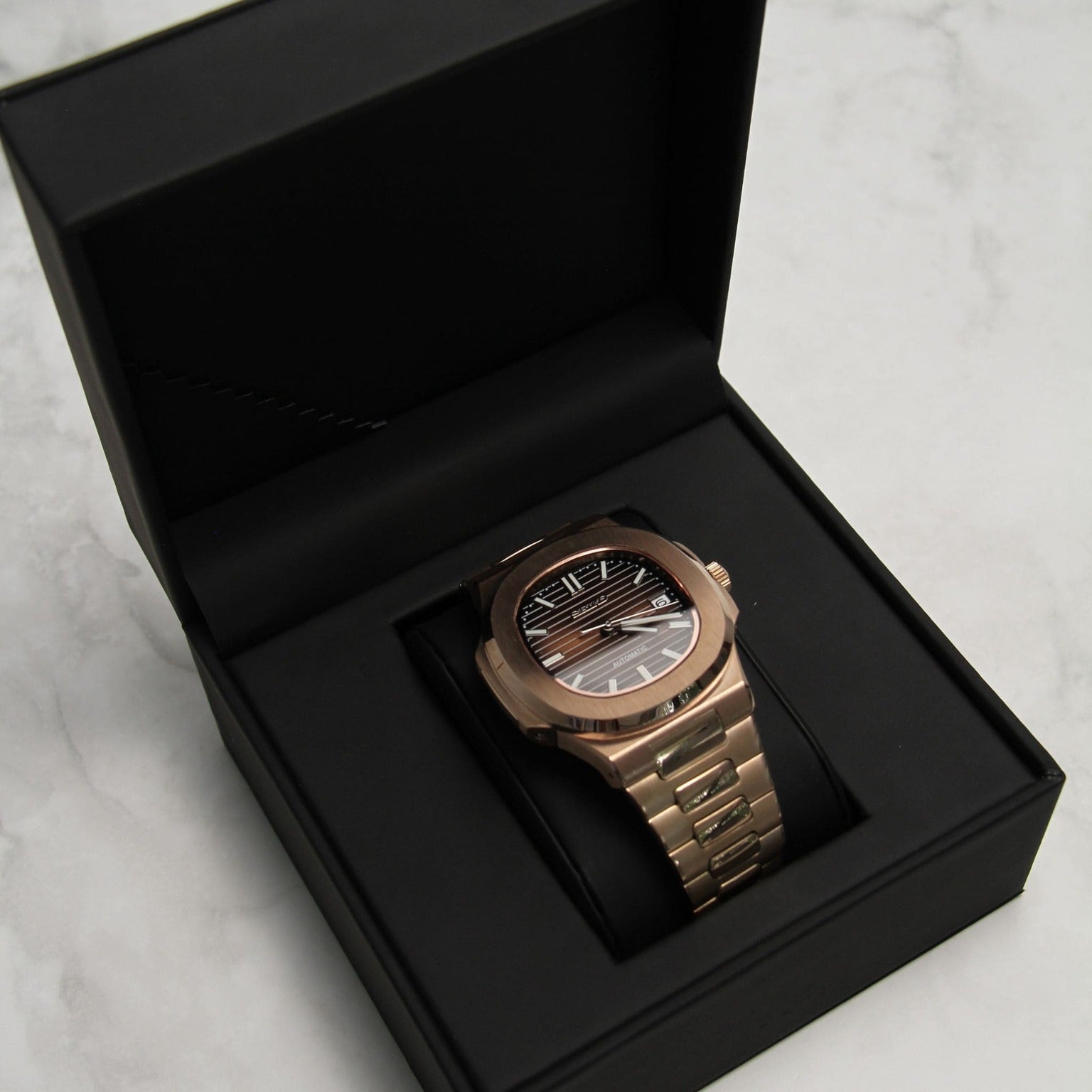Rose gold Seiko Mod Nautilus Chocolate resting in black presentation box on marble surface