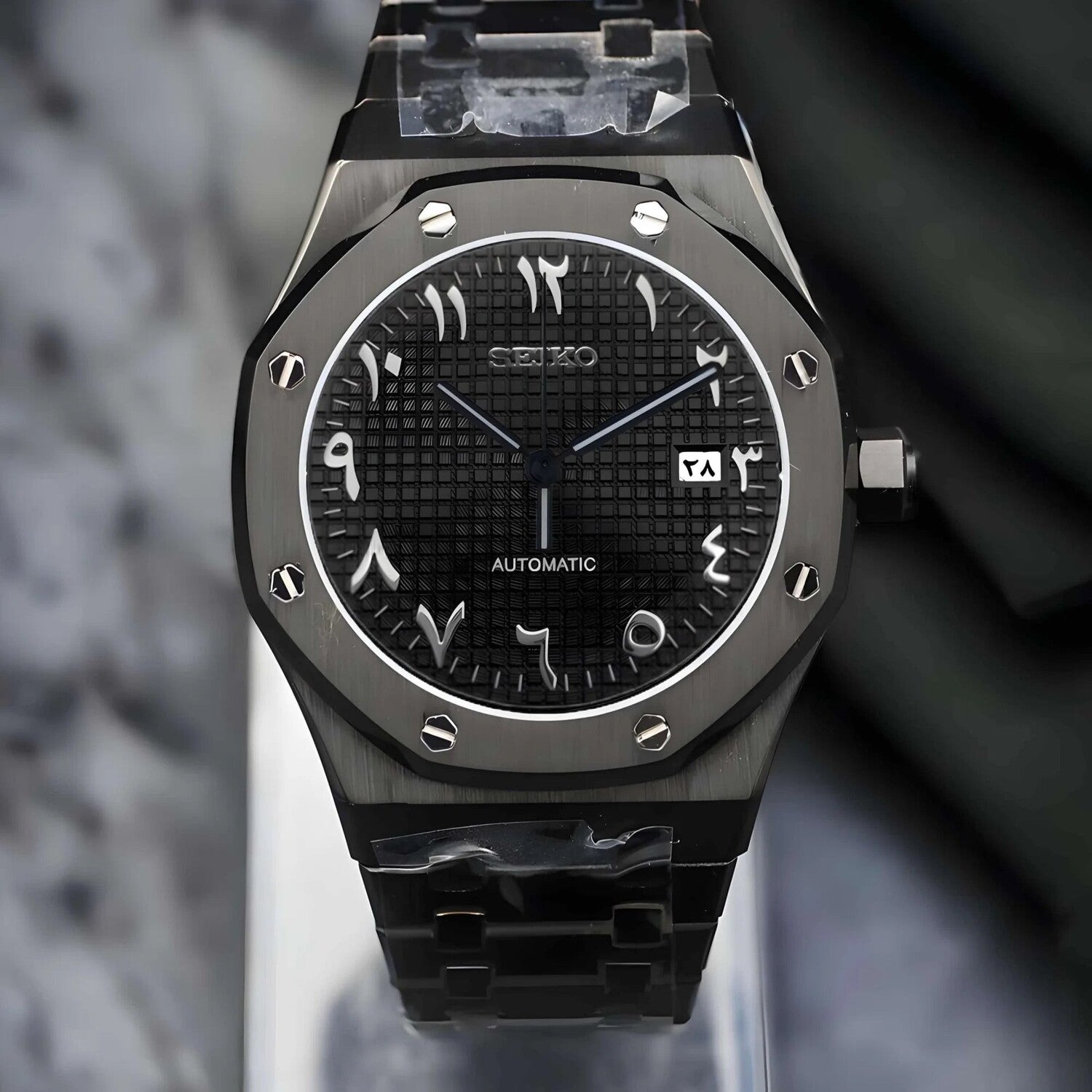 Front view of the Seiko Mod Royal Oak automatic watch with a black Arabic numeral dial, waffle pattern texture, brushed black stainless steel case, and matching steel bracelet