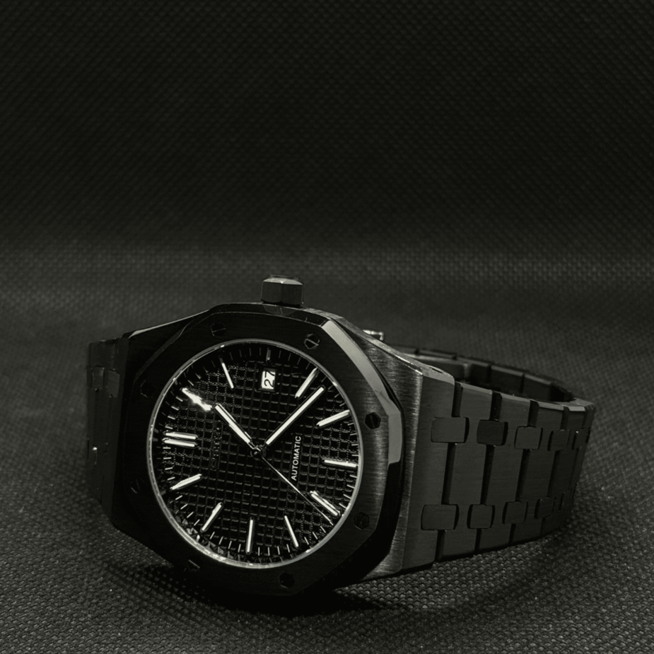 Horizontal view of the Seiko Mod Royal Oak automatic watch in all black, showcasing a waffle pattern dial, brushed stainless steel bracelet, and stealth inspired design against a dark textured background