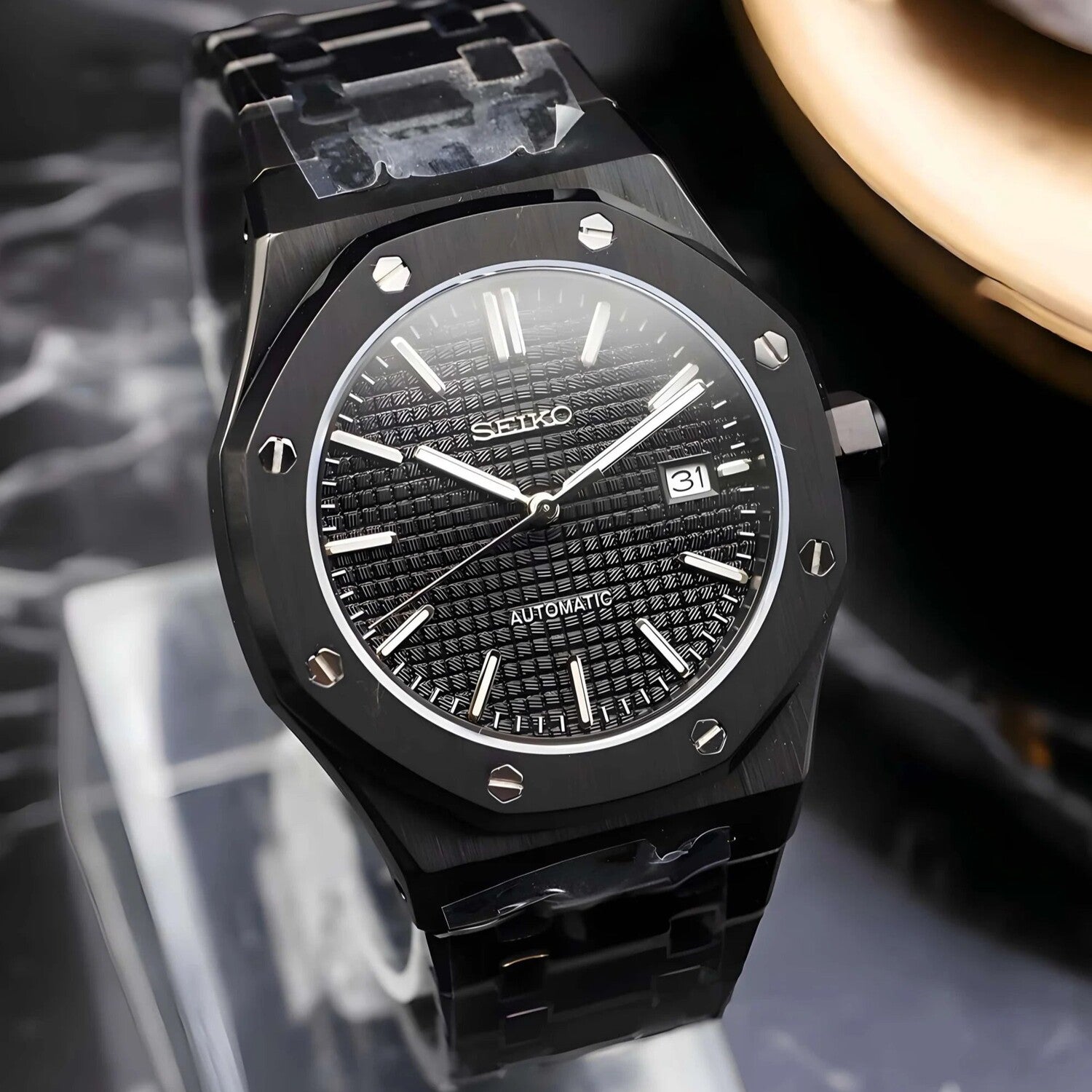 Right three quarter view of the Seiko Mod Royal Oak automatic watch in all black with a waffle pattern dial, brushed stainless steel case, sapphire crystal, and integrated bracelet design