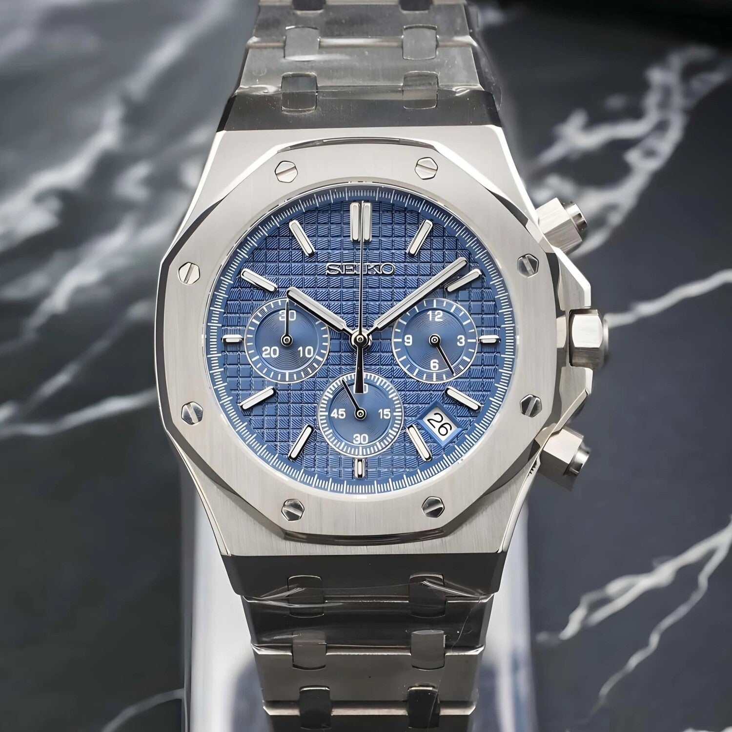 Front view of the Seiko Mod Royal Oak VK63 chronograph with blue waffle pattern dial, three subdials, and a discreet date display near 4 o’clock, completed by a brushed stainless steel case and bracelet