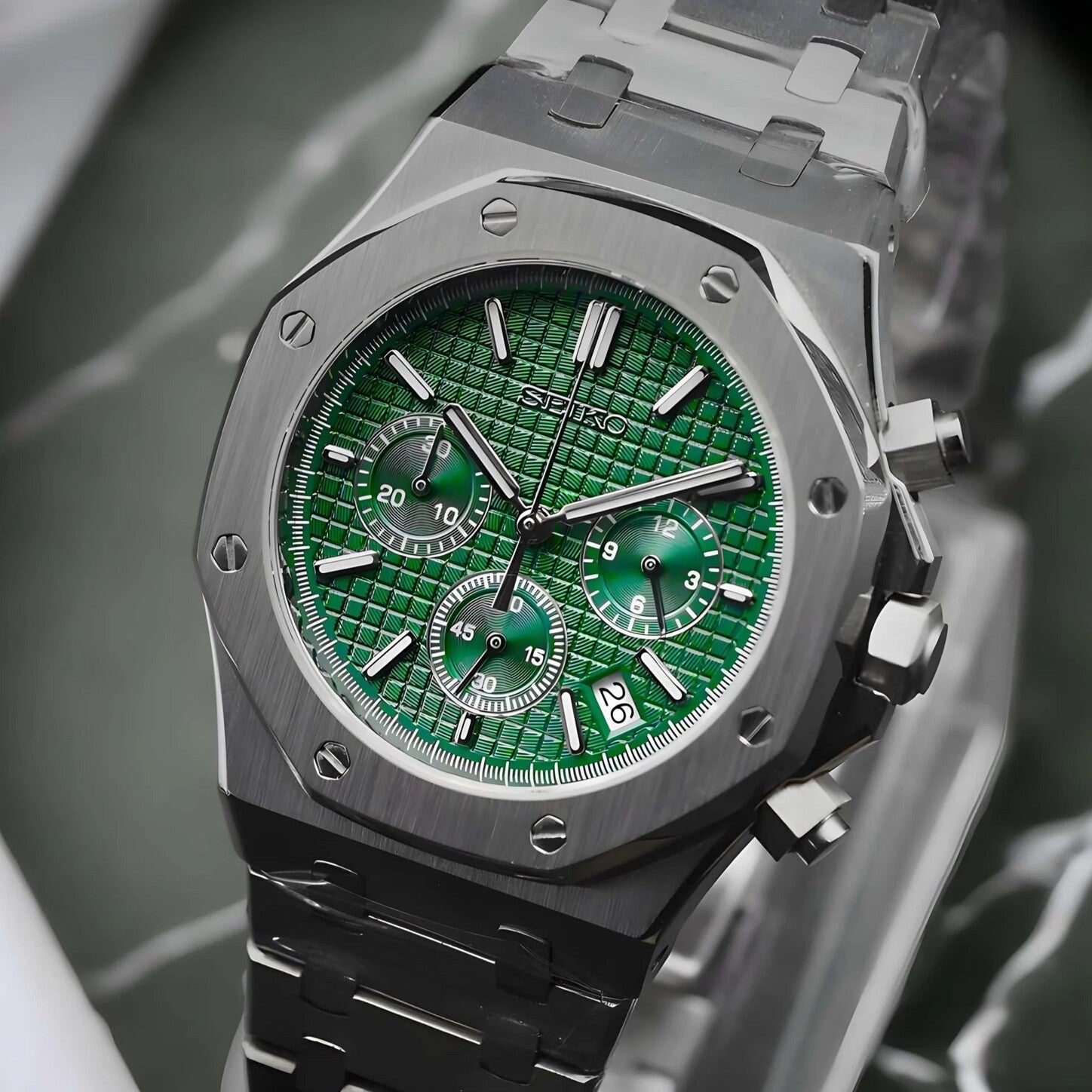 Left angled view of the Seiko Mod Royal Oak chronograph with vibrant green waffle pattern dial, three matching subdials, brushed stainless steel case, polished screw accents, and integrated bracelet.