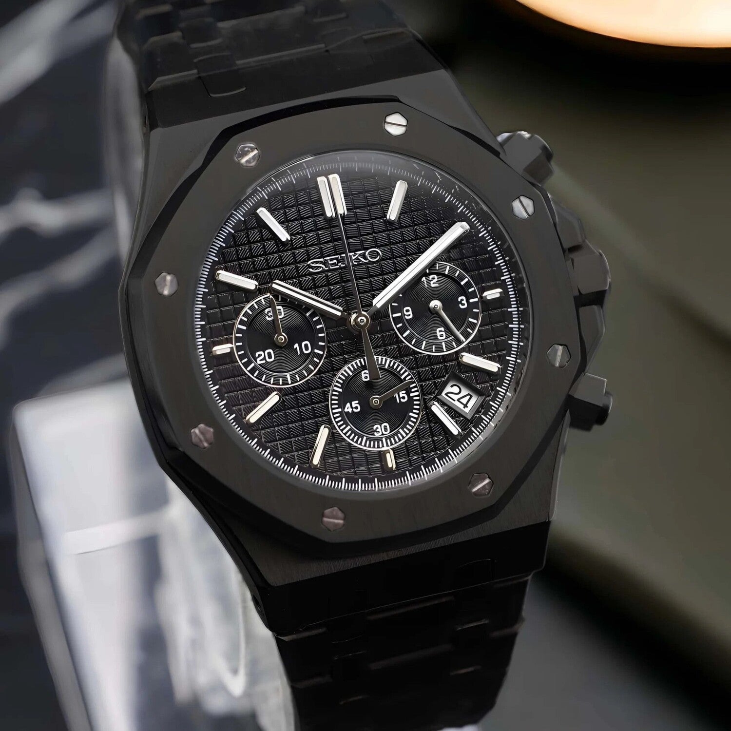 Side view of the Seiko Mod Royal Oak VK63 chronograph in full black, highlighting the brushed stainless steel case, bold chronograph pushers, integrated bracelet, and three functional subdials on the textured dial
