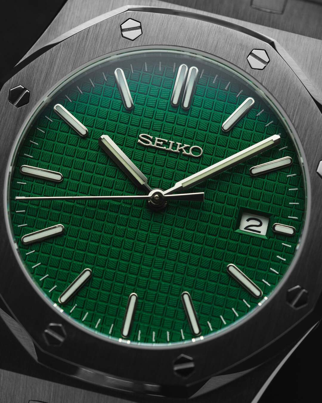 Close up view of the Seiko Mod Royal Oak showcasing its deep green textured dial, applied indices, brushed stainless steel bezel, and date window at three o’clock.