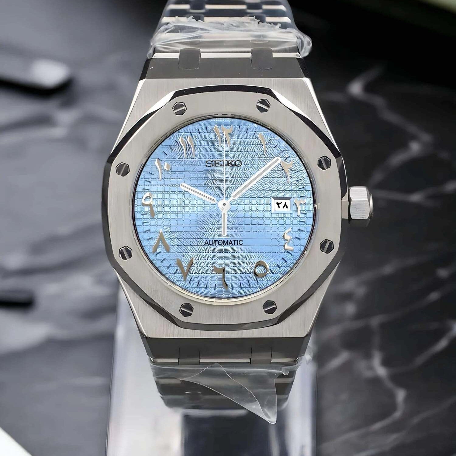 Front view of a Seiko Mod Royal Oak with ice blue textured dial, Arabic numerals, brushed stainless steel case, and matching integrated bracelet.
