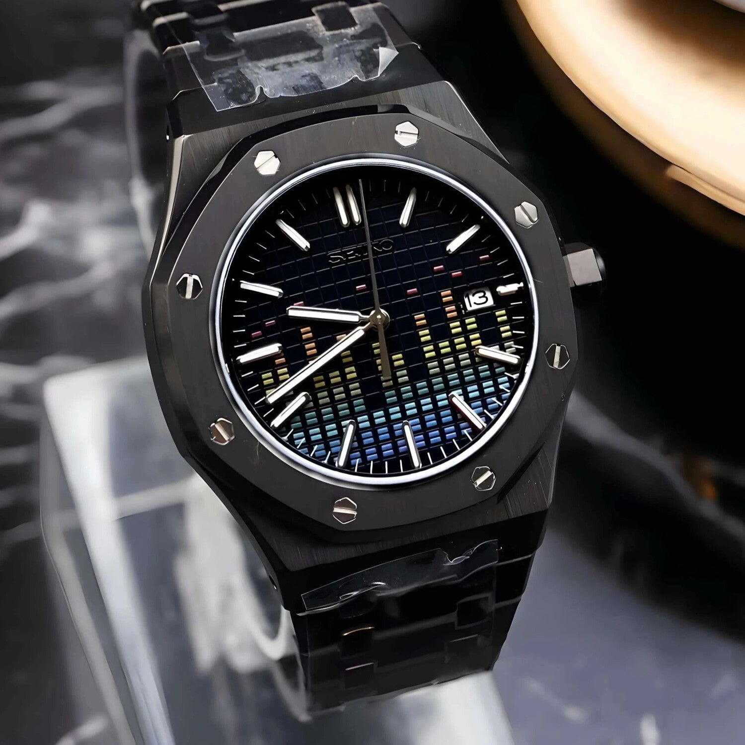 Right-angled close-up view of a Seiko Mod Royal Oak watch showcasing a black dial with colorful music equalizer pattern, octagonal brushed bezel with exposed screws, and a black stainless steel bracelet.