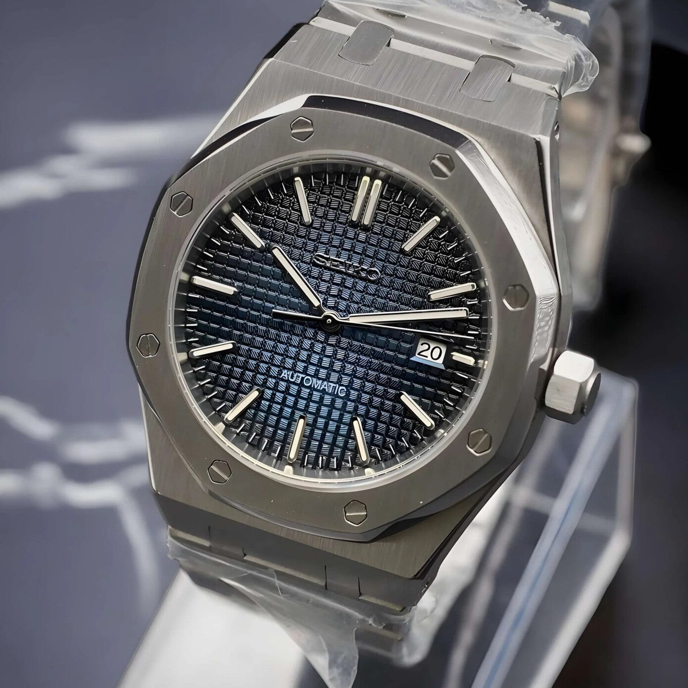 Side angled close up of the Seiko Mod Royal Oak automatic watch with navy blue textured dial, brushed stainless steel case, and date window at three o’clock