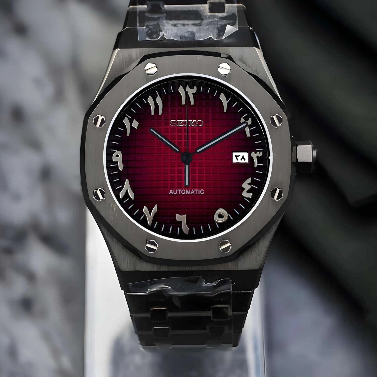 Front view of a Seiko Mod Royal Oak watch featuring a bold red dial with Arabic numerals, a brushed black stainless steel case, and visible screws on the octagonal bezel.