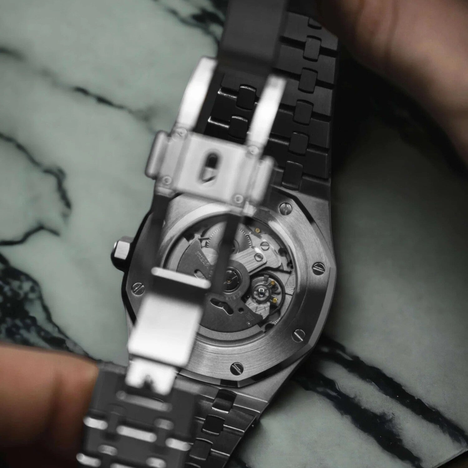 Close up of the Seiko Mod Royal Oak viewed from the bottom, showing the exhibition case back with visible NH35 automatic movement and part of the clasp mechanism in focus.