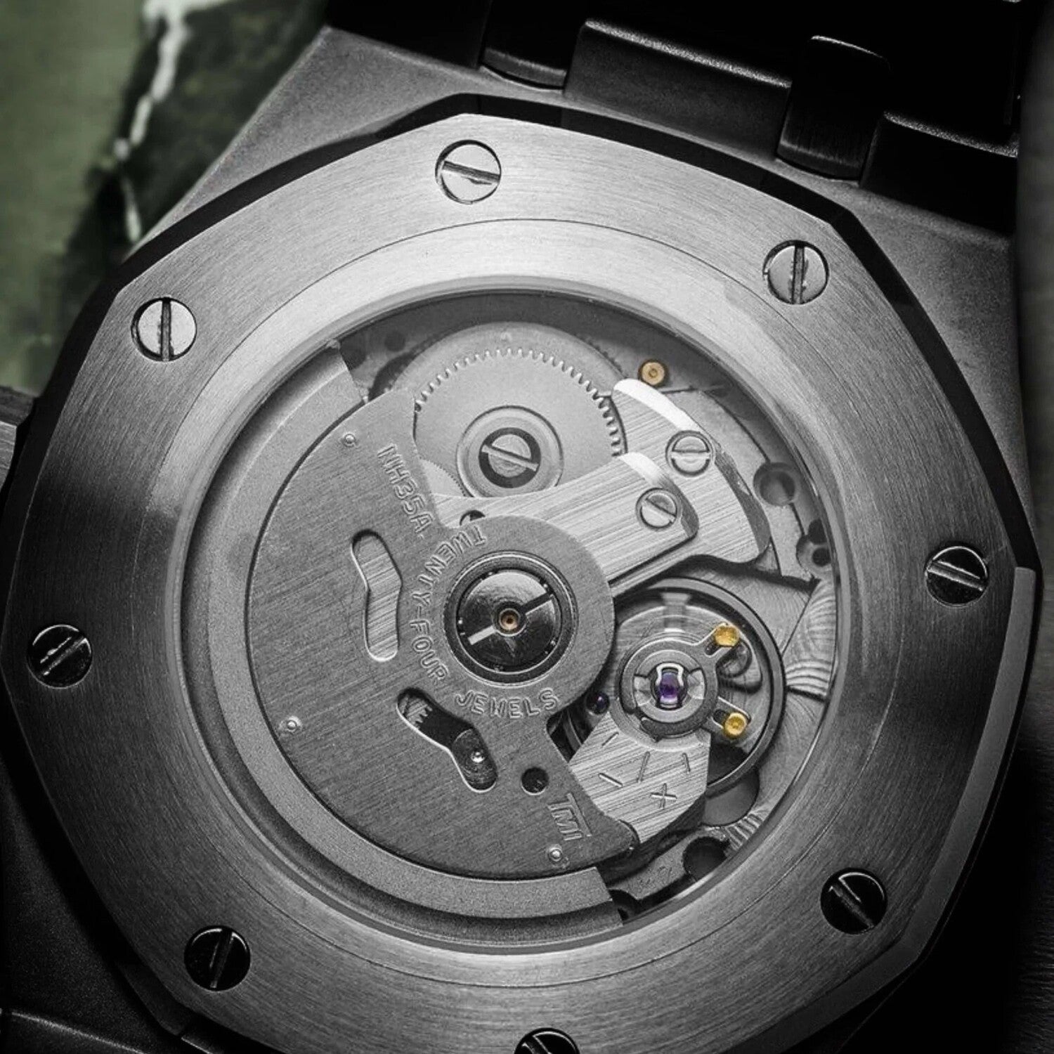 Close up view of the Seiko Mod Royal Oak case back, showcasing the NH35 automatic movement with visible rotor, gears, and polished screws around the brushed steel frame.