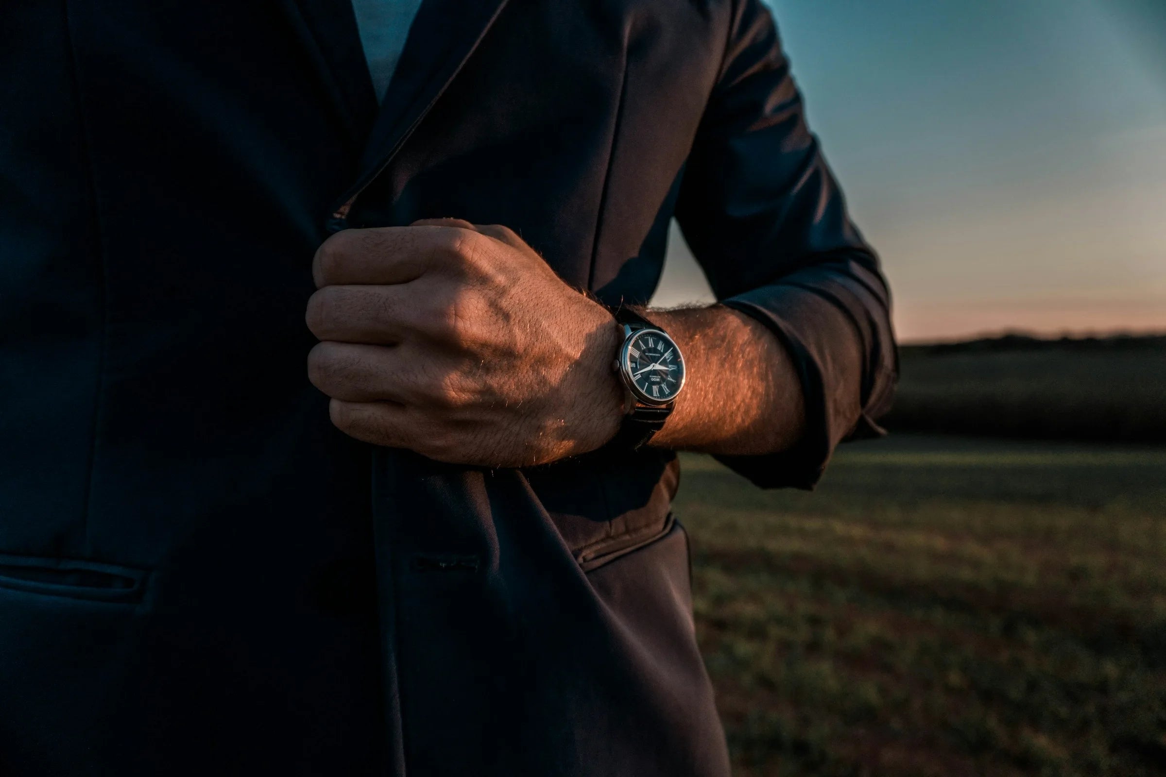 Mann im Anzug trägt eine elegante Seiko Mod Uhr am Handgelenk, aufgenommen im Abendlicht – stilvolle personalisierte Armbanduhr für besondere Anlässe.