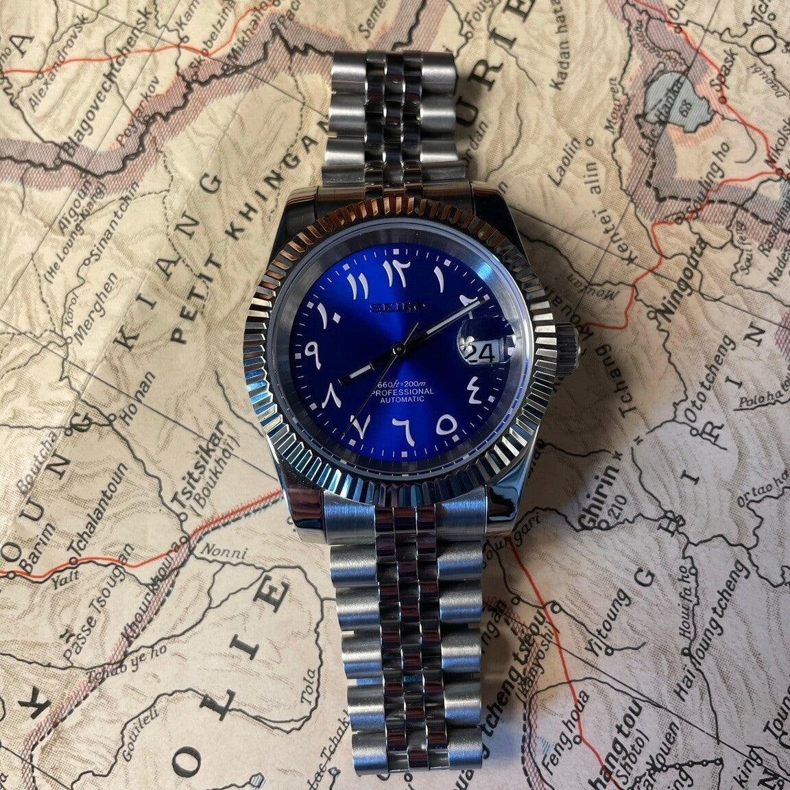 Seiko Mod Datejust Royal Blue Arabic watch flat lay on map highlighting dial and bracelet details
