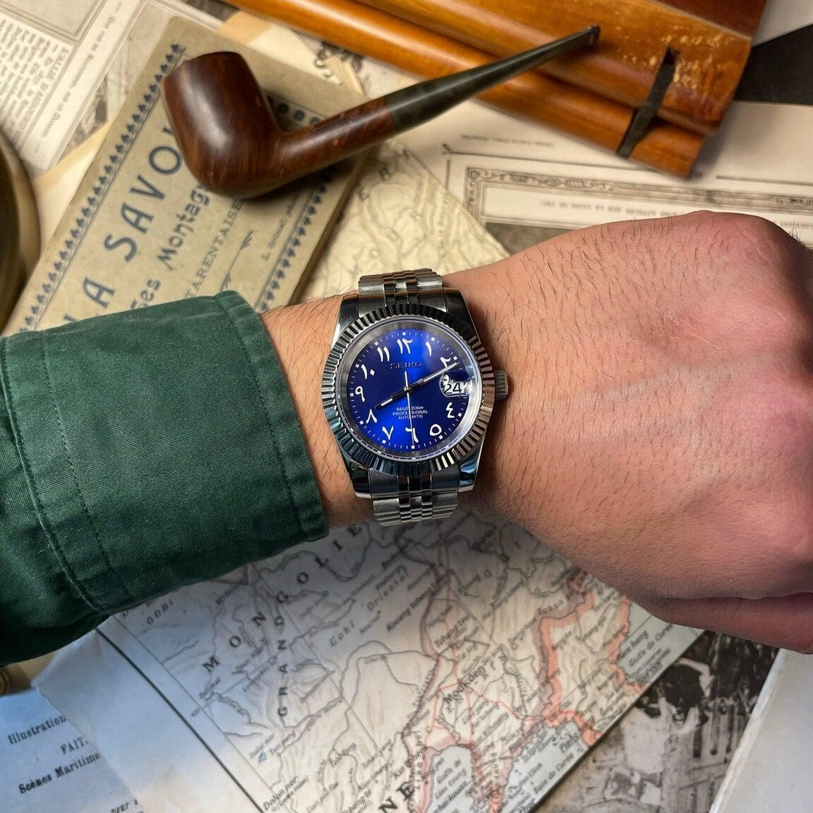 Seiko Mod Datejust Royal Blue Arabic on wrist close up with green shirt and vintage map background