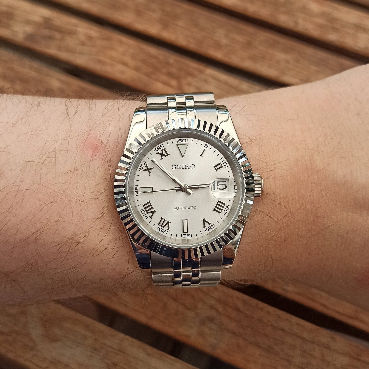 Wrist shot highlighting silver Roman dial of Seiko Mod Datejust in daylight