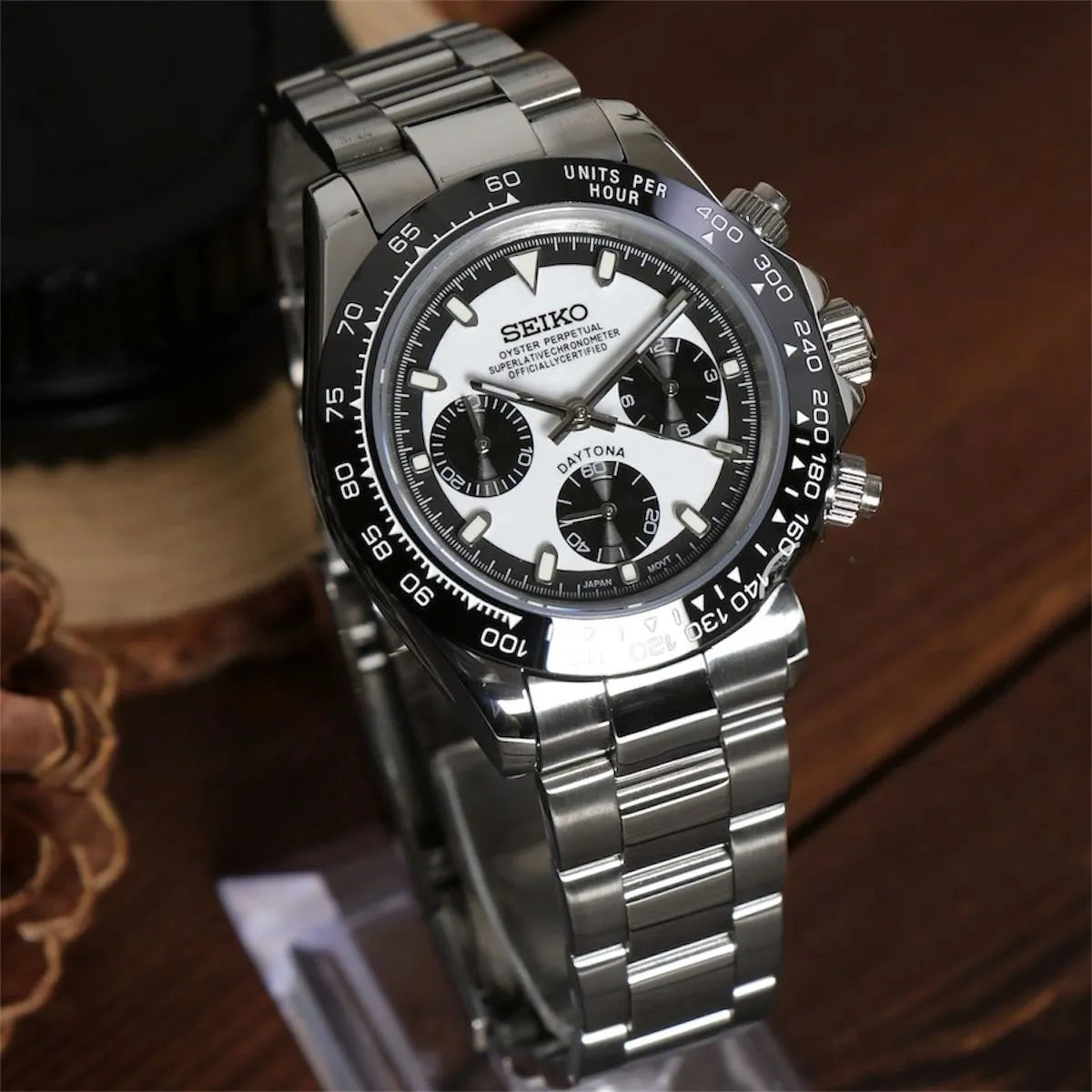 Seiko Mod Daytona in left angled view with black ceramic bezel, white dial, contrasting black subdials and steel bracelet.