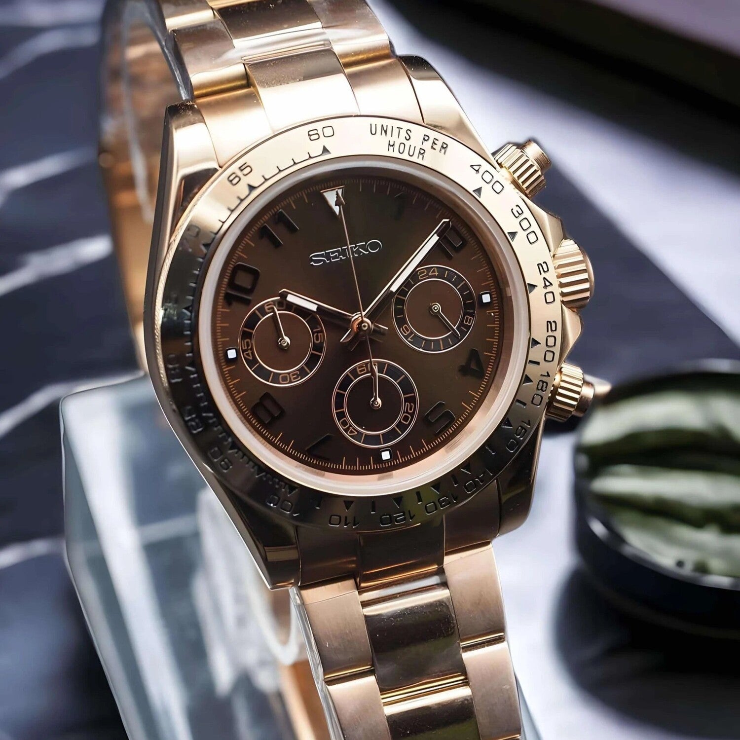 Left-angled view of the Seiko Mod Daytona in rose gold with chocolate dial  polished bracelet visible with glossy reflections.