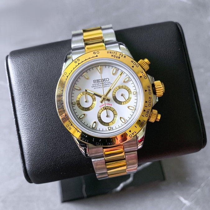 Seiko Mod Daytona two tone steel and gold watch, white dial with gold subdials, displayed on a black leather watch stand.