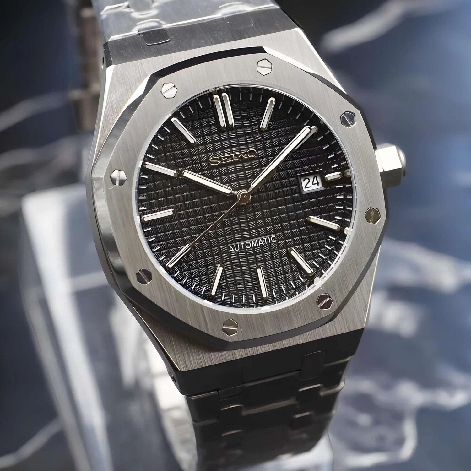Angled view of the Seiko Mod Royal Oak automatic watch with black waffle-pattern dial, brushed stainless steel case, and date window at 3 o’clock