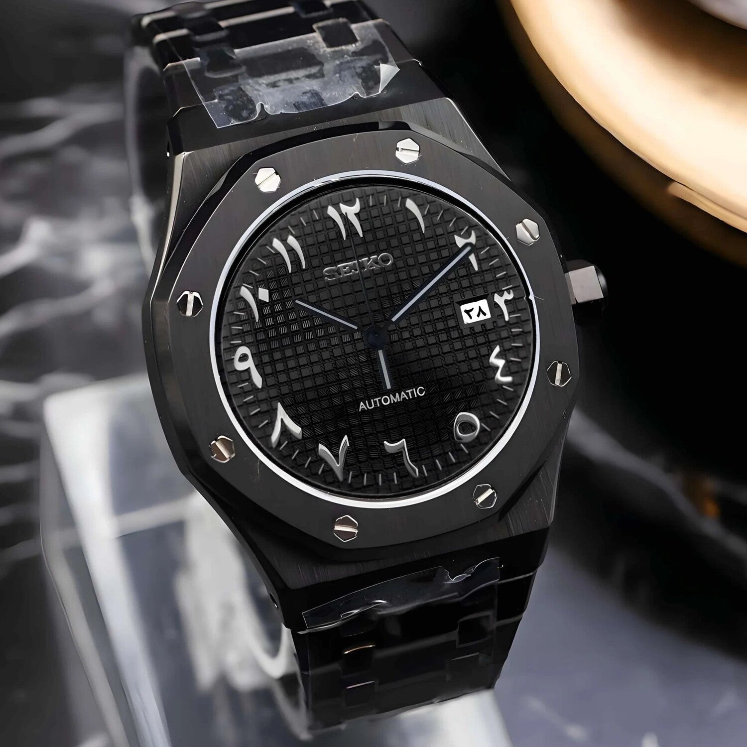 Right angled view of the Seiko Mod Royal Oak automatic watch featuring a black Arabic numeral dial with waffle pattern texture, brushed black stainless steel case, and matching black bracelet