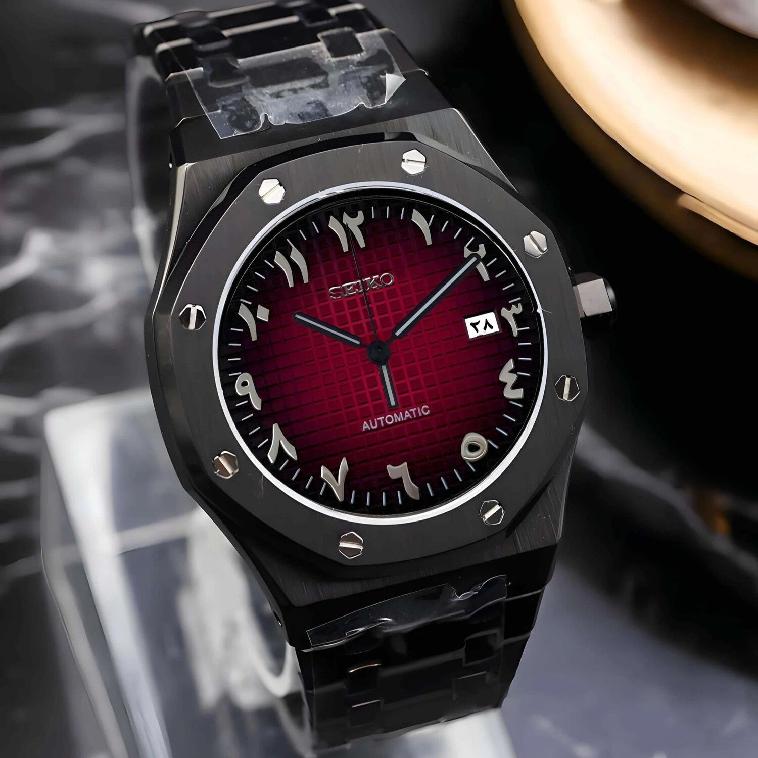 Right angled close up view of a Seiko Mod Royal Oak watch featuring a deep red textured dial with Arabic numeral indices, brushed black octagonal bezel secured with polished screws, and a black stainless steel bracelet.