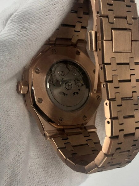 Bottom view of the Seiko Mod Royal Oak in rose gold, highlighting the transparent case back that reveals the automatic movement, surrounded by a brushed rose gold case and integrated bracelet with polished links.