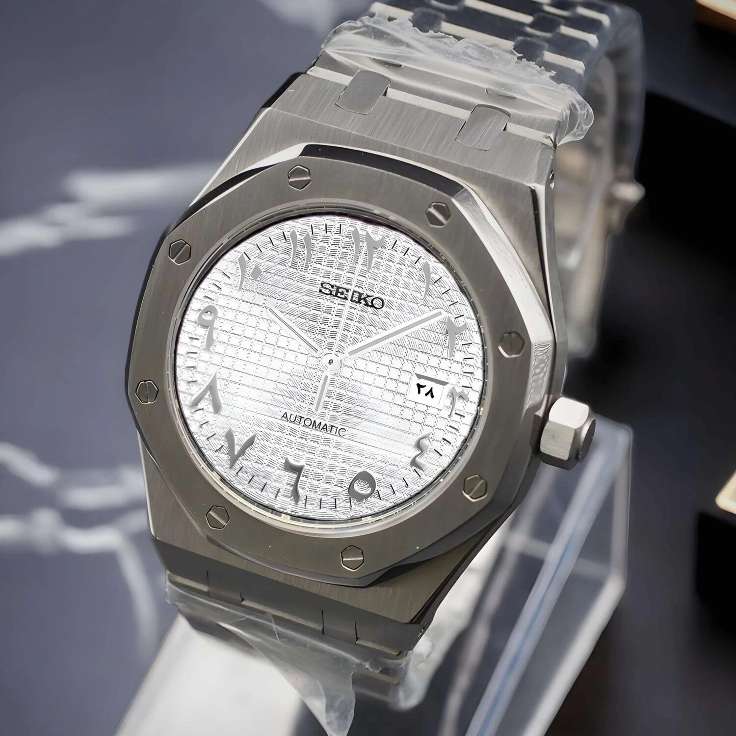 Seiko Mod Royal Oak with brushed steel case shown from a right angled view, highlighting the white textured dial with Arabic numerals and a date window at three o’clock.